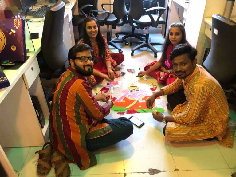 Team making a rangoli in the office during a festival