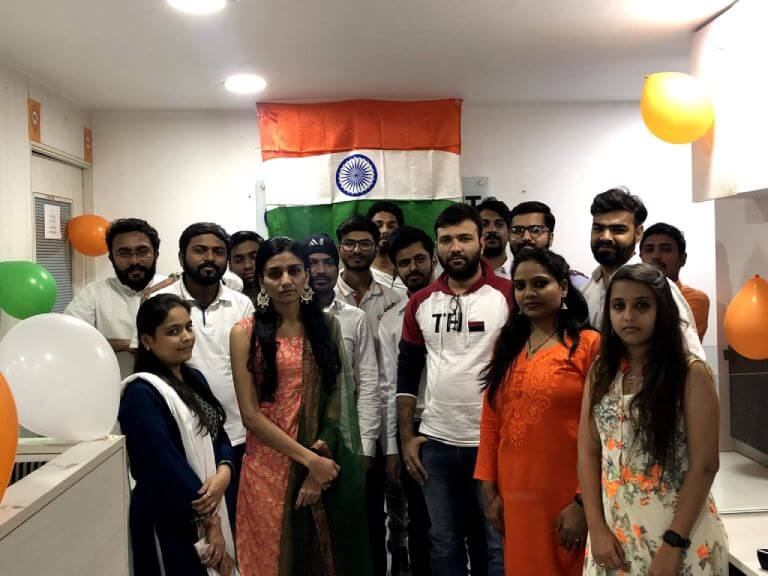Team celebrating a company milestone with balloons and the Indian flag